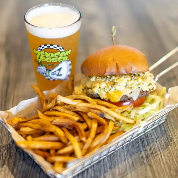 Cheeseburger with lettuce and tomato, served with golden fries and a Mexican Logger beer.